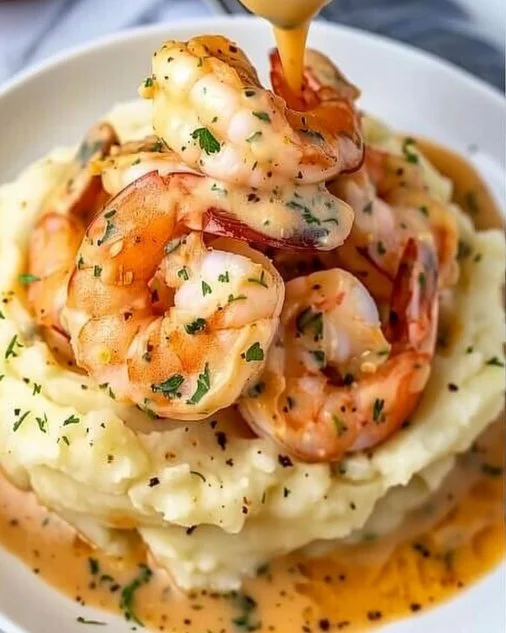 Creamy Garlic Shrimp Over Mashed Potatoes 2 Creamy garlic shrimp served over a bed of mashed potatoes, garnished with parsley.
