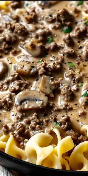 Creamy beef stroganoff served with pasta and fresh parsley.