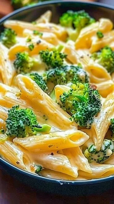 Creamy broccoli cheese pasta served in a bowl garnished with herbs