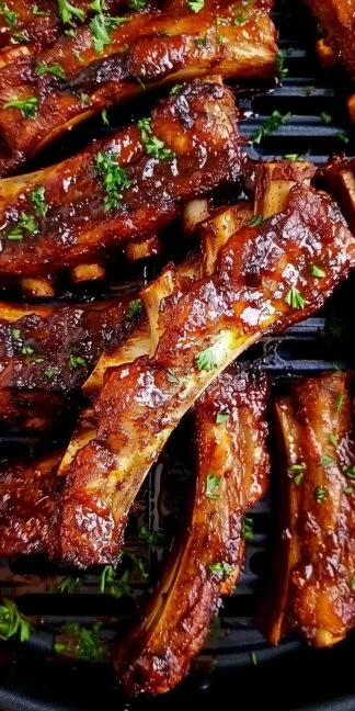Crispy air fryer ribs served on a plate, garnished with herbs.