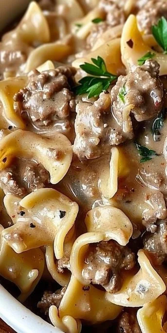 Delicious bowl of Ground Beef Stroganoff served with pasta and garnished with parsley.