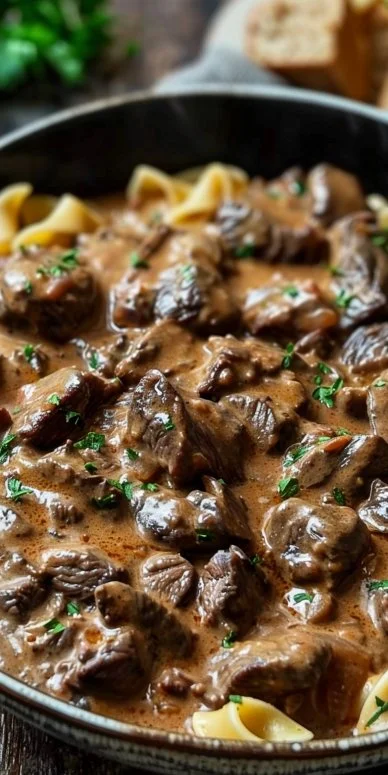 Creamy Beef Stroganoff served over egg noodles, garnished with fresh herbs.