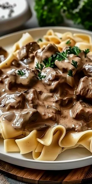 Delicious creamy beef stroganoff served with egg noodles and garnished with parsley.