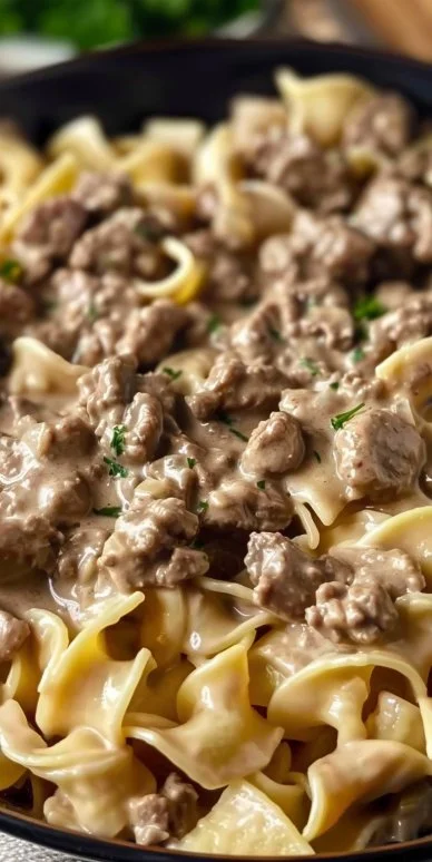 Creamy ground beef stroganoff served on a plate with pasta and garnish