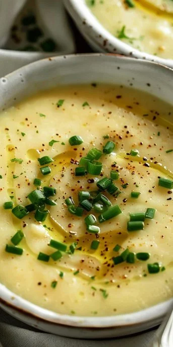 Bowl of creamy potato leek soup garnished with fresh herbs