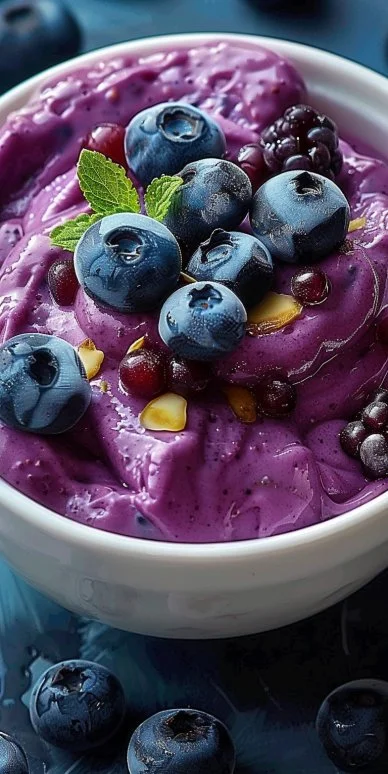 Fresh blueberry yogurt topped with juicy blueberries in a clear bowl