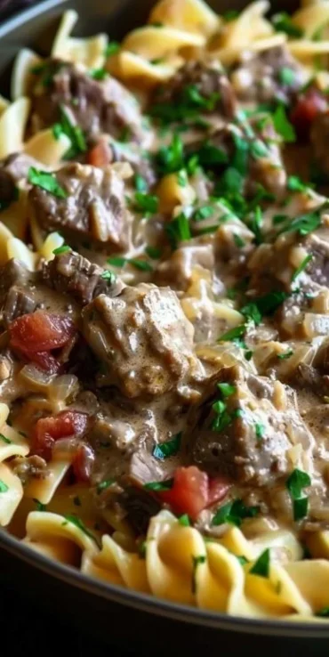 Bowl of slow cooked beef stroganoff pasta garnished with fresh herbs.
