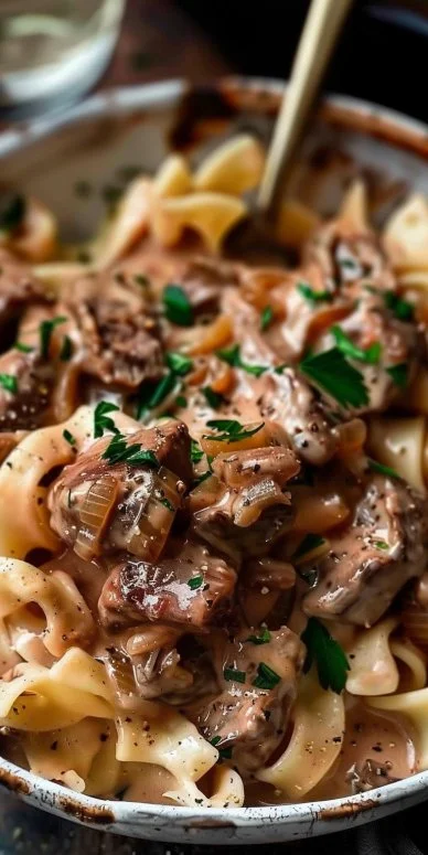 World's Best Beef Stroganoff 4 Delicious beef stroganoff served in a bowl with noodles and garnished with parsley