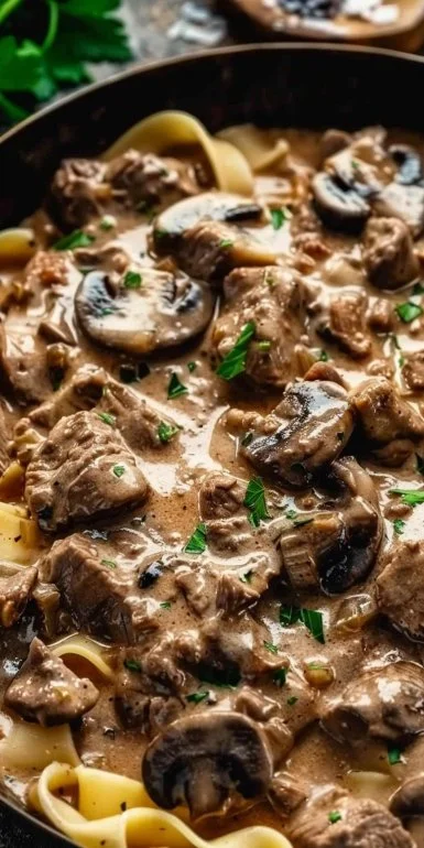 Delicious Beef Stroganoff served over egg noodles with fresh herbs.