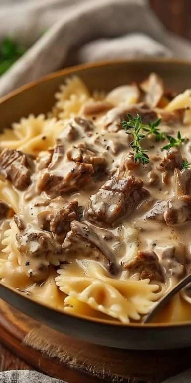 Creamy beef stroganoff with bowtie pasta garnished with parsley in a bowl
