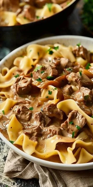 Hearty Crock Pot Beef Stroganoff served with noodles and parsley garnish