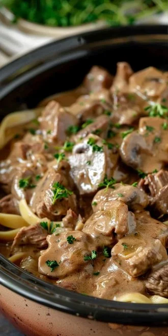 Crock Pot Beef Stroganoff 4 Delicious Crock Pot Beef Stroganoff served in a bowl with noodles and herbs