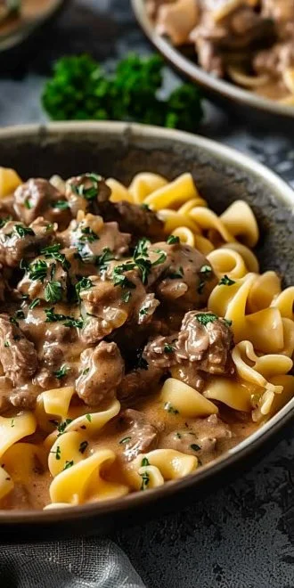 A warm bowl of Ground Beef Stroganoff topped with parsley and served with egg noodles