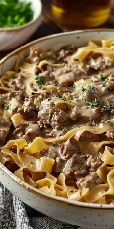 Homemade ground beef stroganoff served on a plate with noodles and garnish