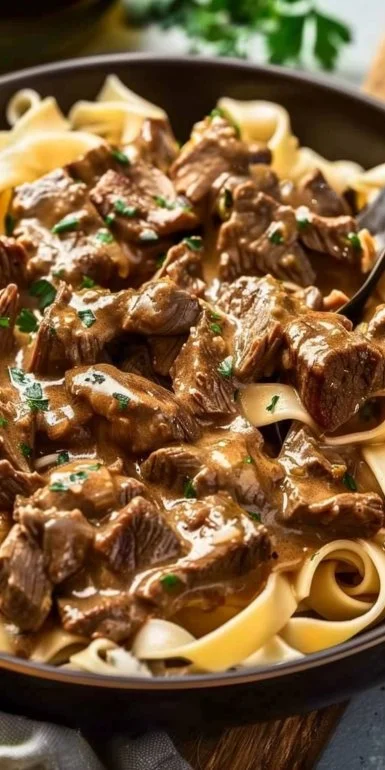 Creamy old fashioned beef stroganoff served with egg noodles and garnished with parsley.