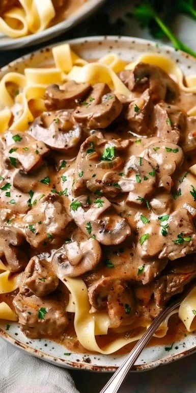Delicious quick beef stroganoff served in a bowl with noodles and fresh herbs