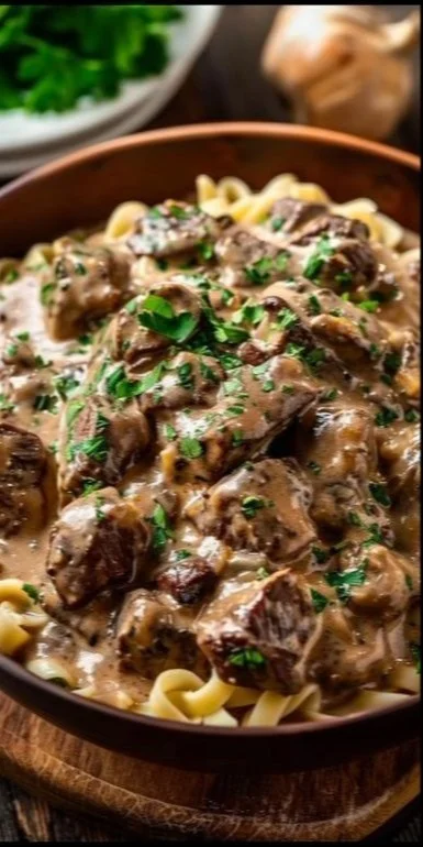 Delicious slow cooker beef stroganoff served with noodles and garnished with parsley