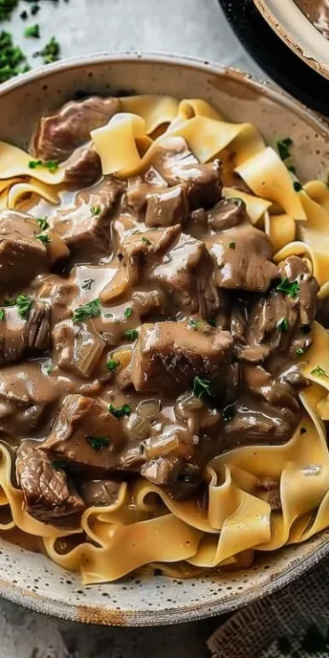 Delicious slow cooker beef stroganoff served with pasta and fresh herbs