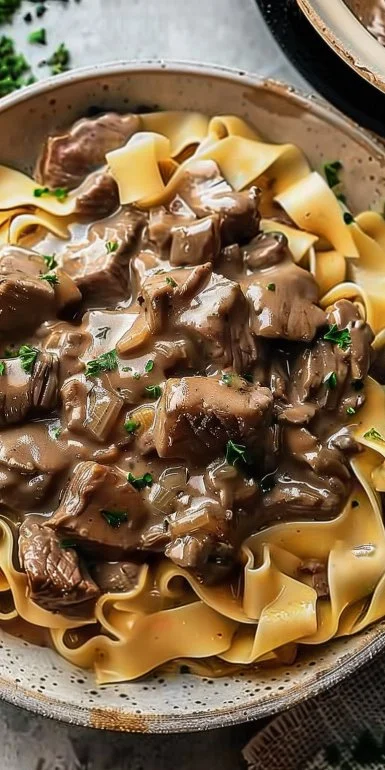 Delicious slow cooker beef stroganoff served with pasta and fresh herbs