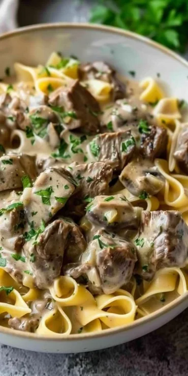 Crock pot beef stroganoff served in a creamy sauce with noodles and mushrooms