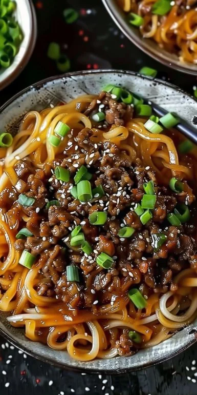 Delicious plate of Mongolian Ground Beef Noodles garnished with vegetables.